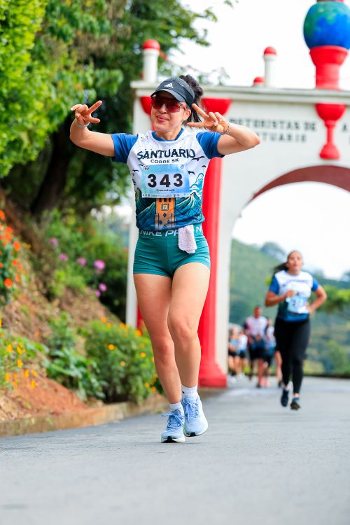 Free Woman running a marathon, smiling and making peace sign during the race. Stock Photo