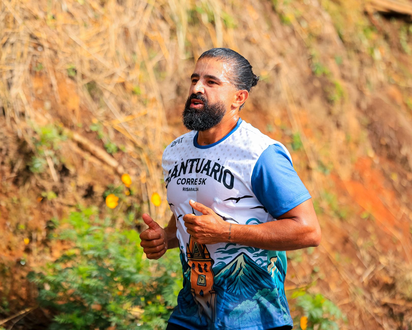 Bearded man participating in a 5K run outdoors wearing a scenic illustrated shirt.