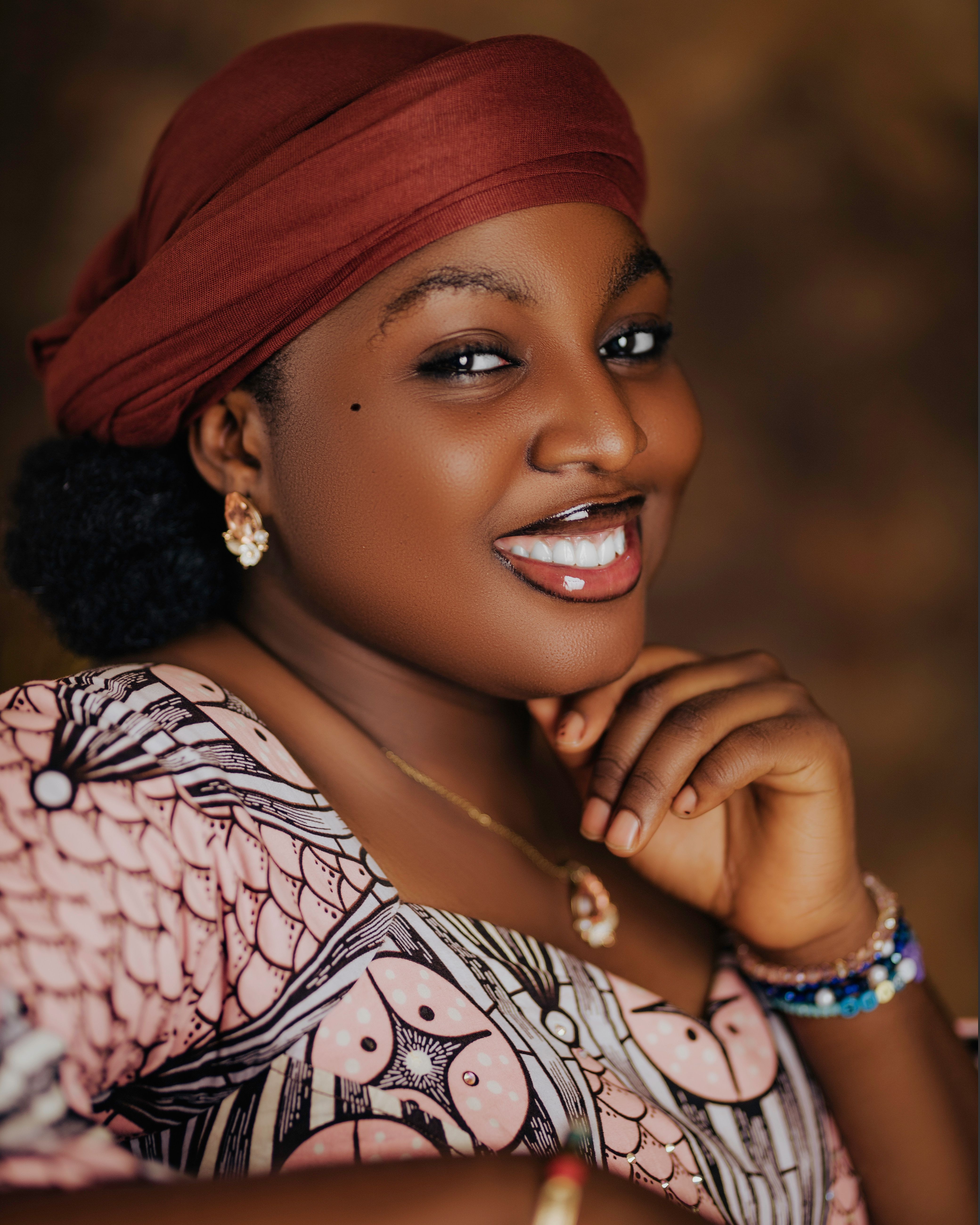 African woman in traditional attire smiles warmly with a classic pose.