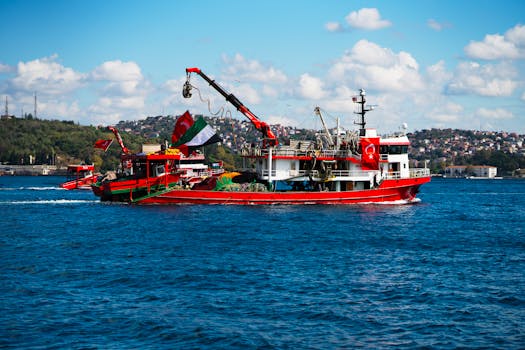 在土耳其伊斯坦布尔，一艘充满活力的红色渔船在蔚蓝的天空下航行在博斯普鲁斯海峡上