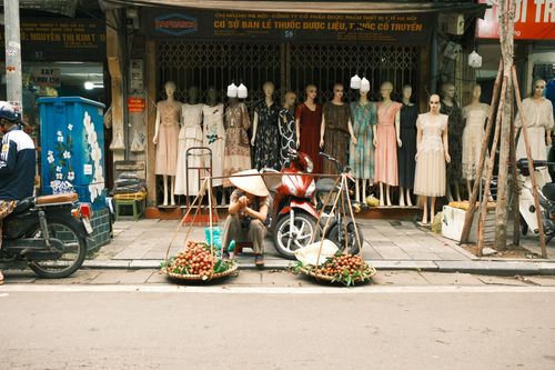 Free A street vendor sells fruit in front of a clothing shop in Jakarta, Indonesia. Stock Photo