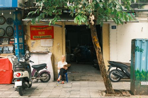 Free An elderly woman sitting outside a shop in Jakarta, Indonesia, on a vibrant city street. Stock Photo