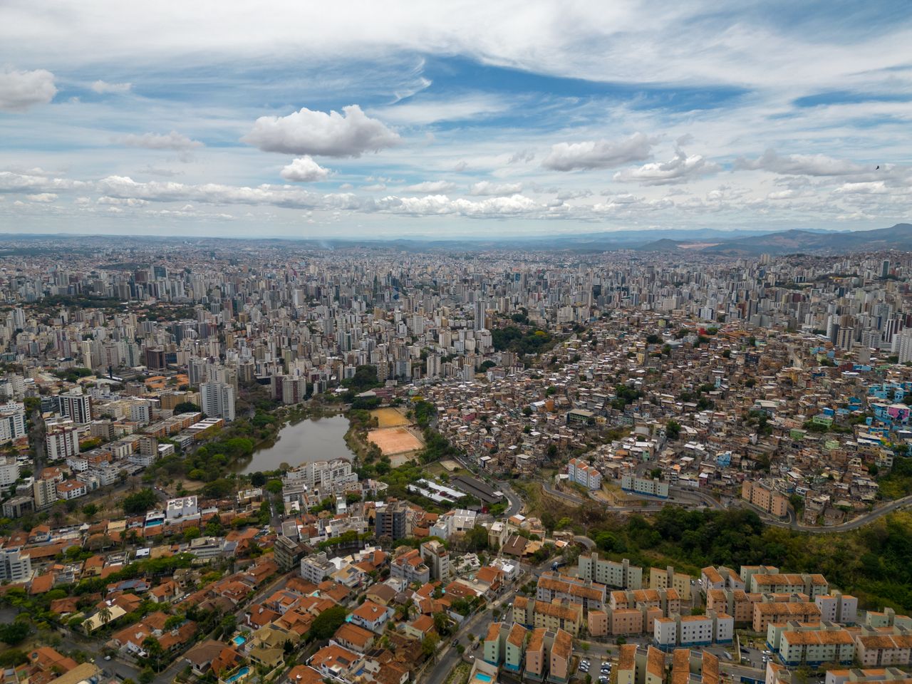 Panorama urbano de cidade brasileira ao entardecer, com prédios residenciais e comerciais.