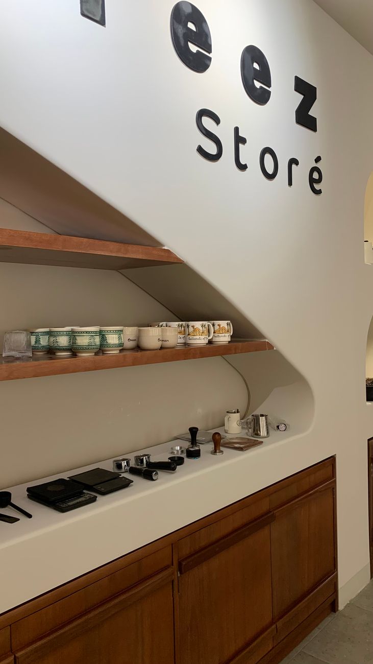 Stylish coffee shop interior featuring neatly arranged coffee cups and equipment on wooden shelves.