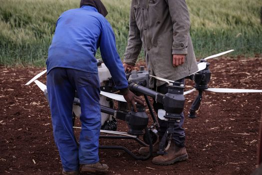 Two farmers working with a drone for crop surveillance in a field, showcasing modern agricultural technology.