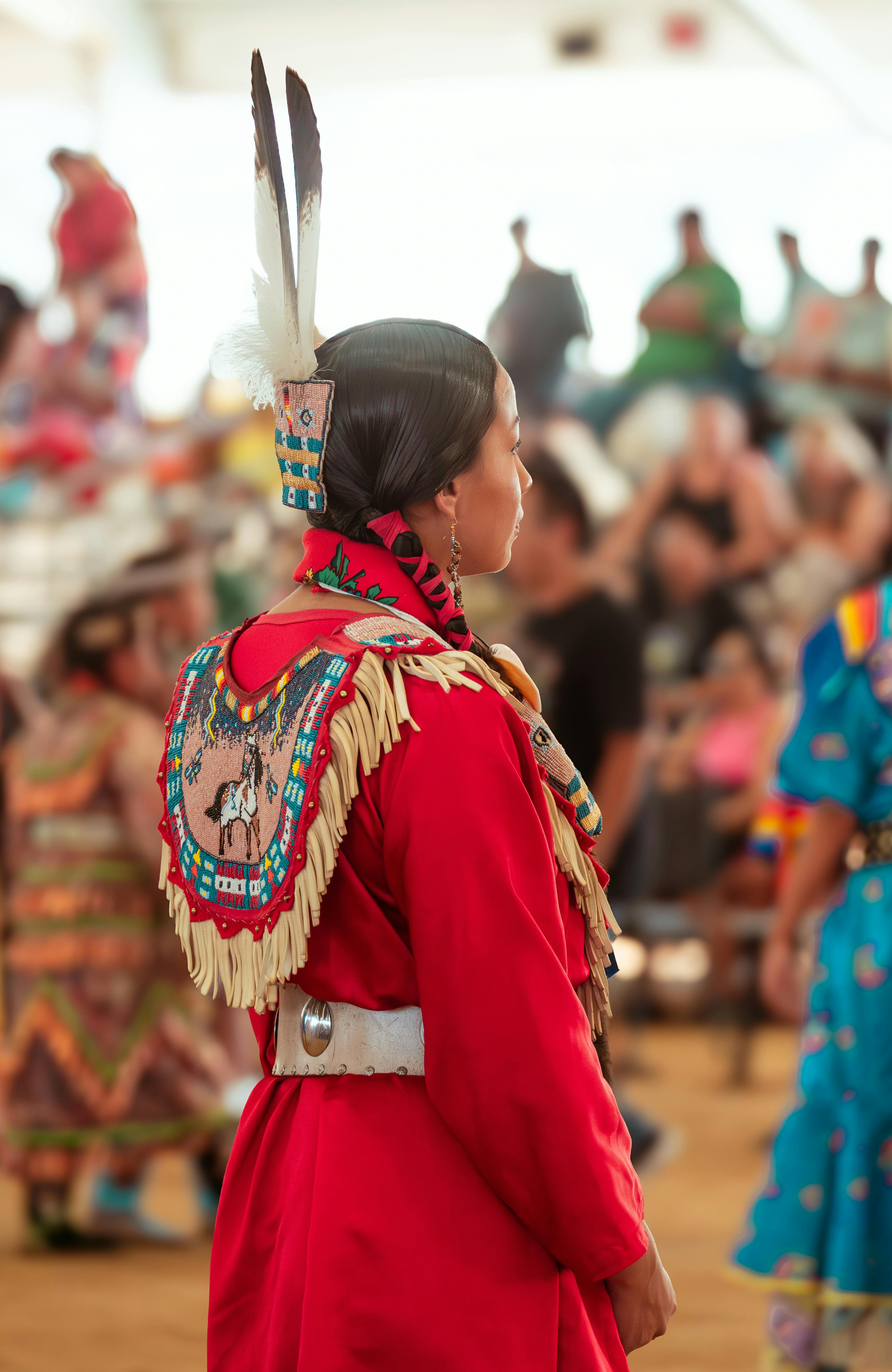Native American woman in traditional red attire participating in a vibrant cultural powwow.