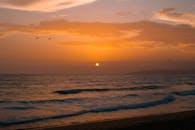 宁静的海滩氛围被平静的海浪和令人惊叹的日落所营造