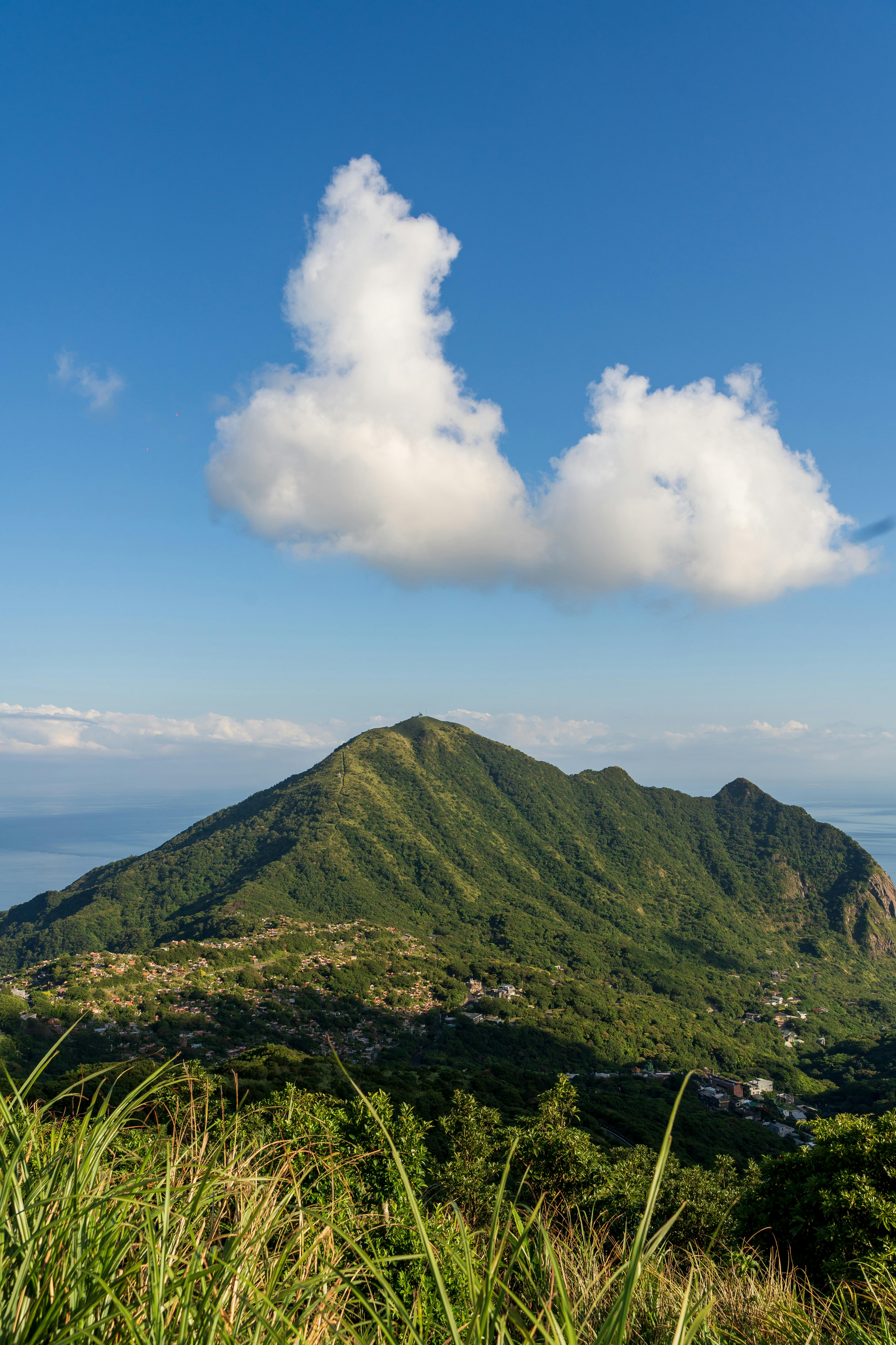 在蔚蓝的天空和白色的云层之下，郁郁葱葱的青山令人惊叹