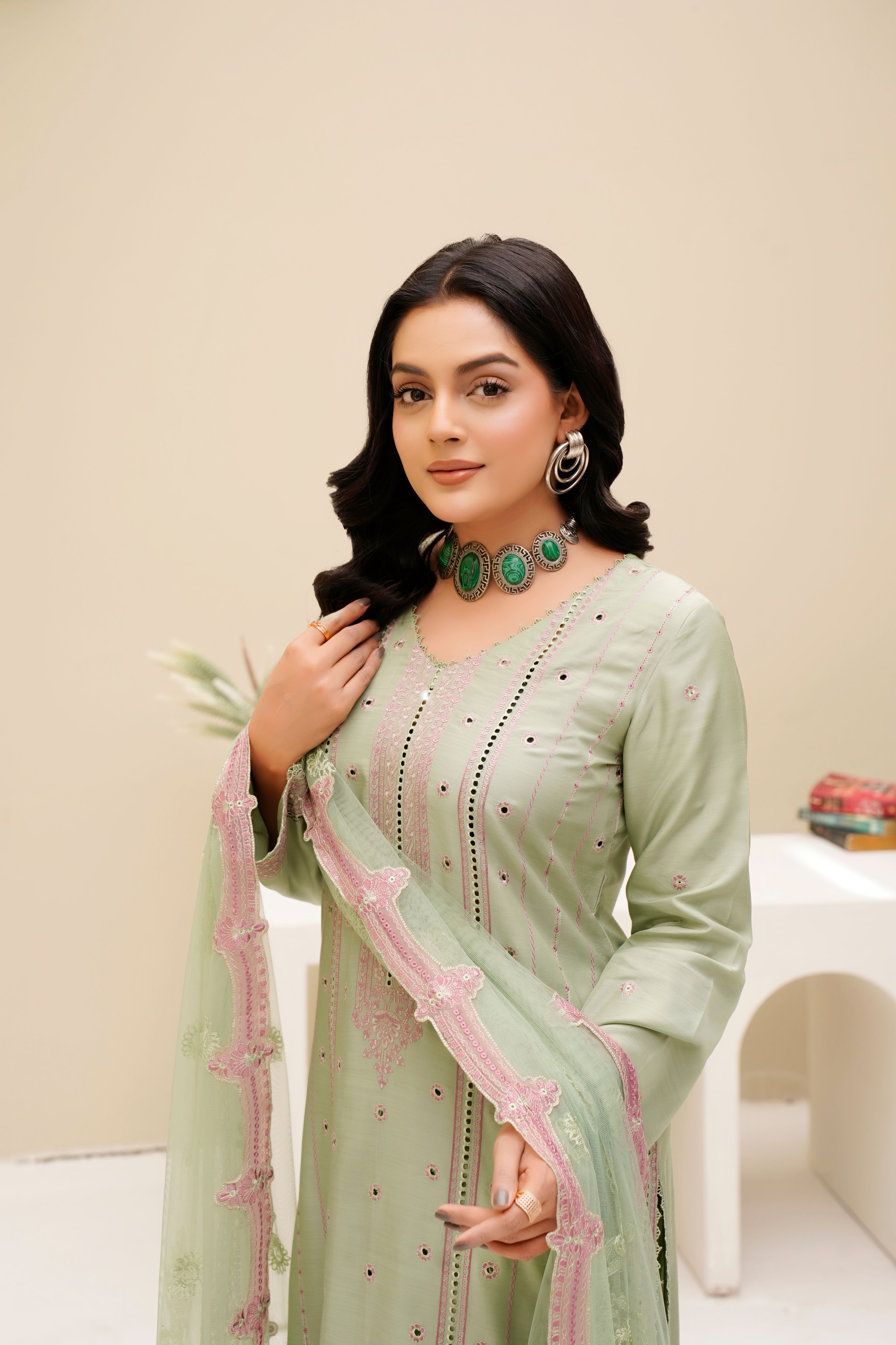 Stylish fashion model in green eastern dress with jewelry in Lahore studio setting.