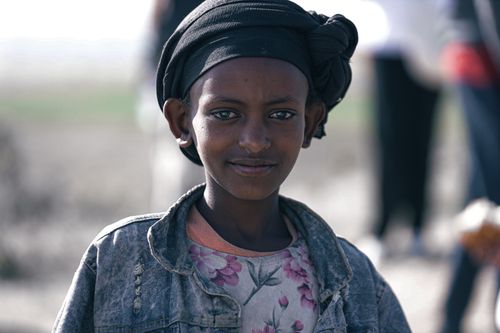 Free A young girl with a headscarf smiles outdoors, showcasing cultural attire. Stock Photo