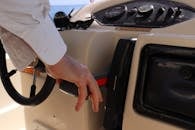 一个人正通过船只控制面板调整油门，同时在屏幕上突出显示了相关动作和导航信息