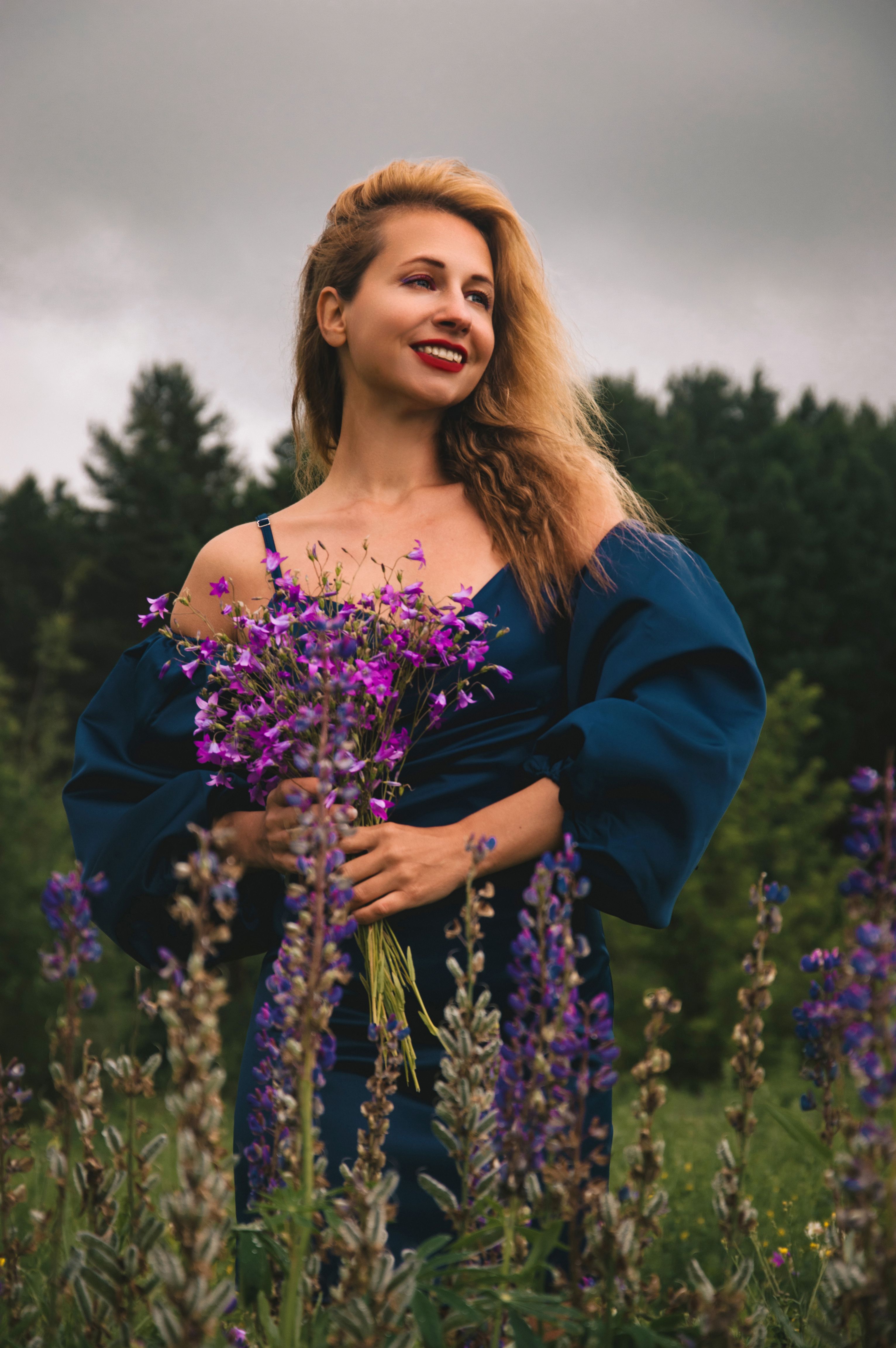 Woman in blue dress holding wildflowers in meadow · Free Stock Photo