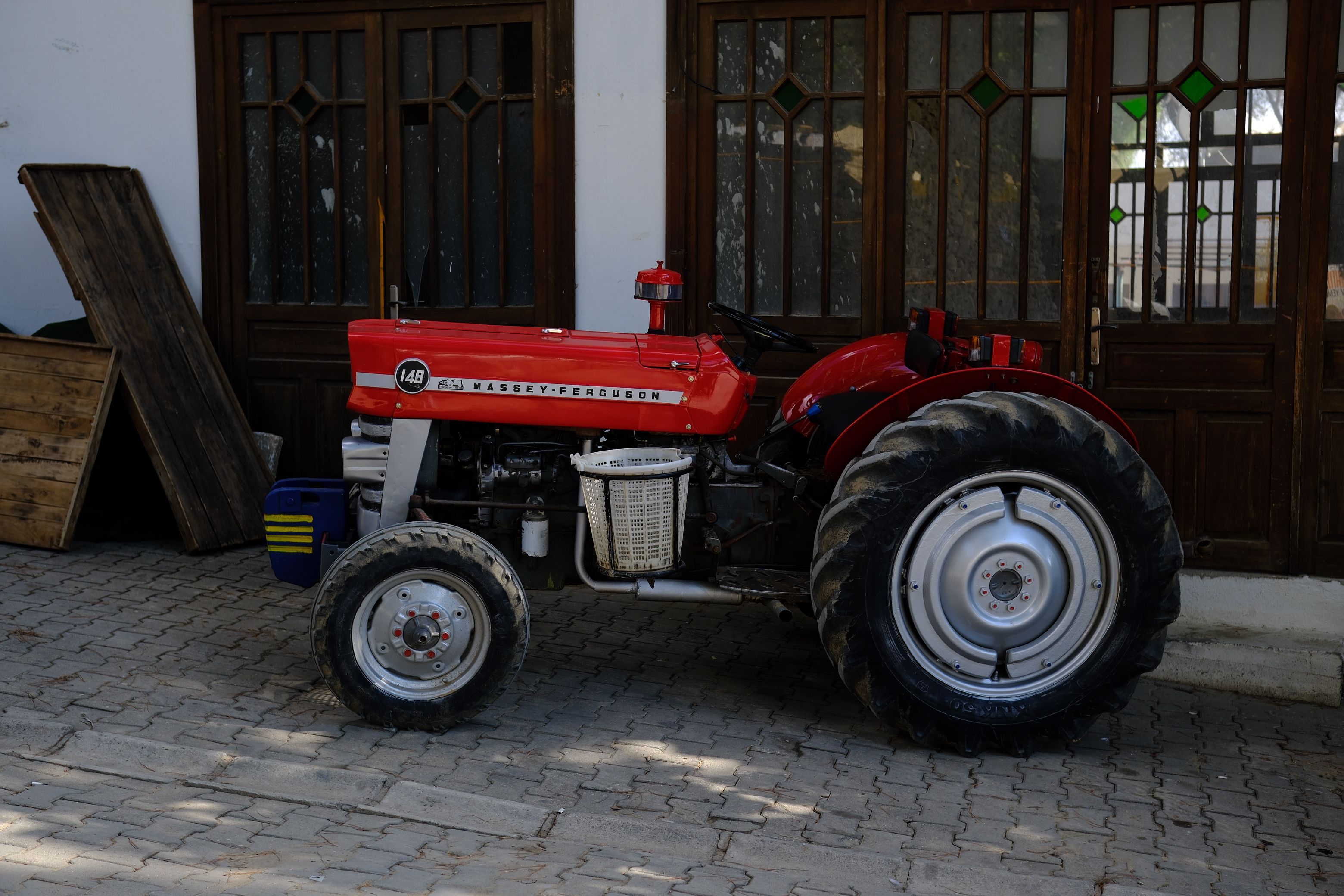 Red Massey Ferguson tractor parked outside with wooden doors in the background.