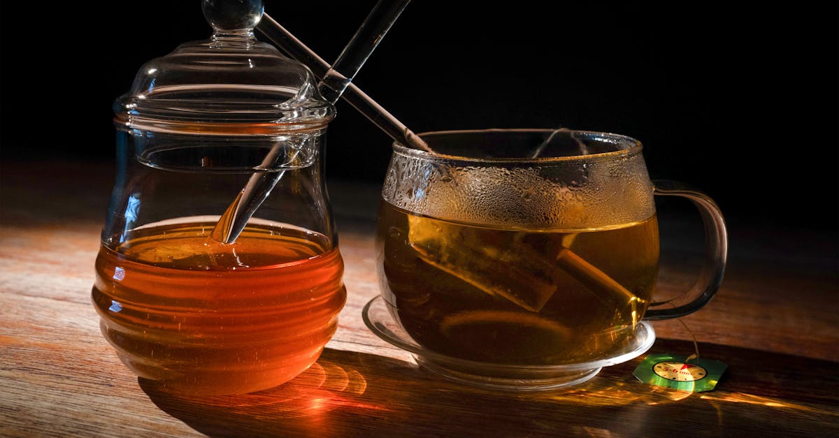 A cozy setting featuring a steaming cup of herbal tea beside a honey jar on a wooden table, perfect for relaxation.