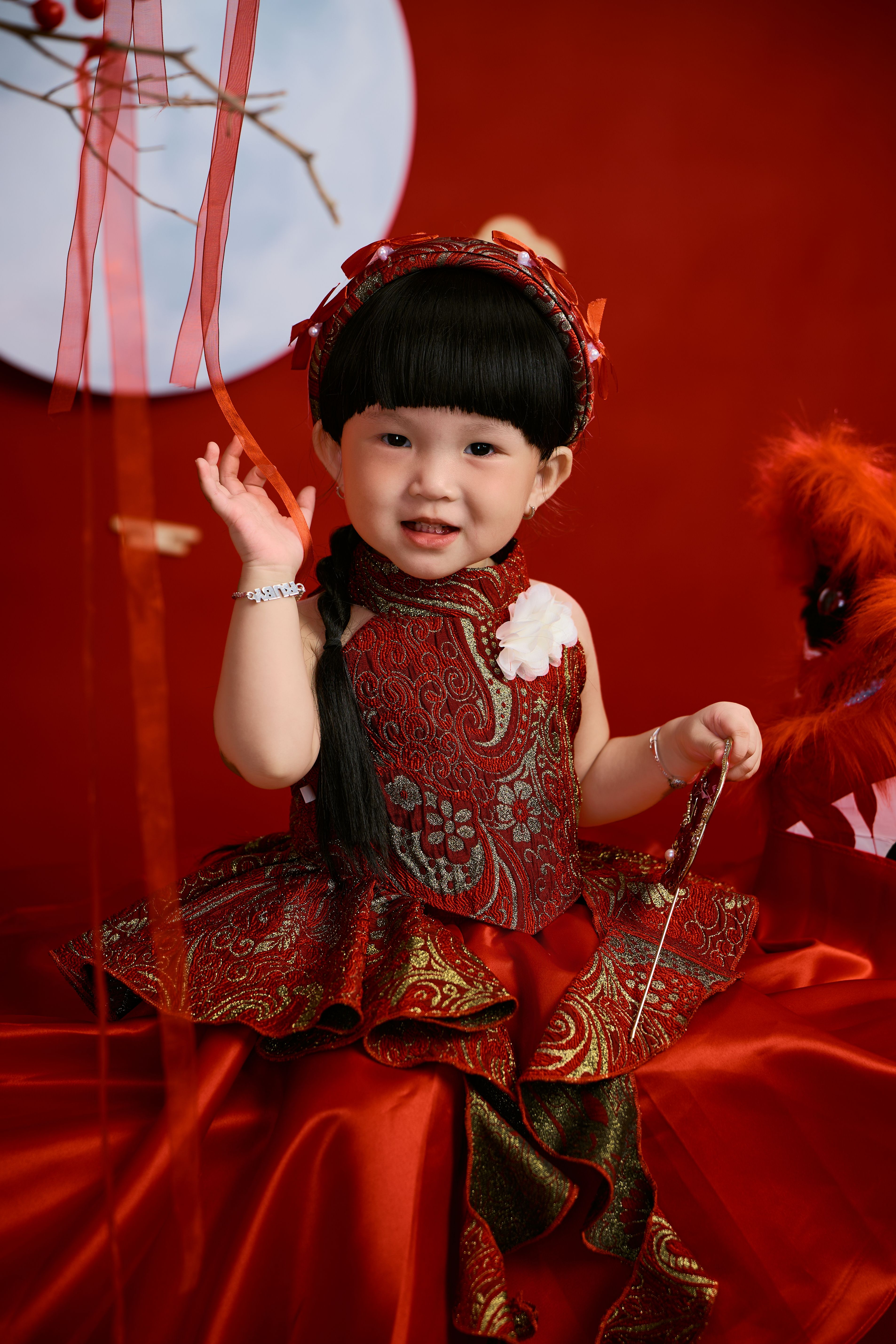 Cute child in red traditional costume celebrating with decorations.