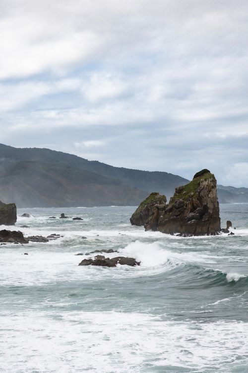 Free Dramatic waves crash against the rocky cliffs of Gaztelugatxe in the Basque Country. Stock Photo