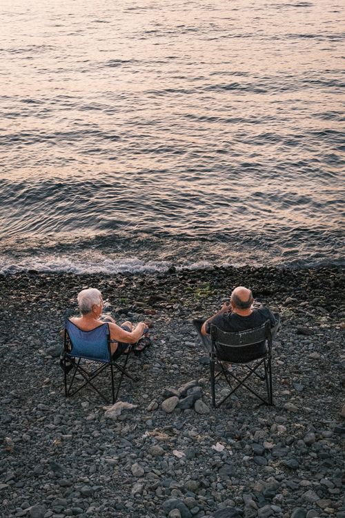 Free A serene scene of an elderly couple enjoying a peaceful moment by the water's edge. Stock Photo
