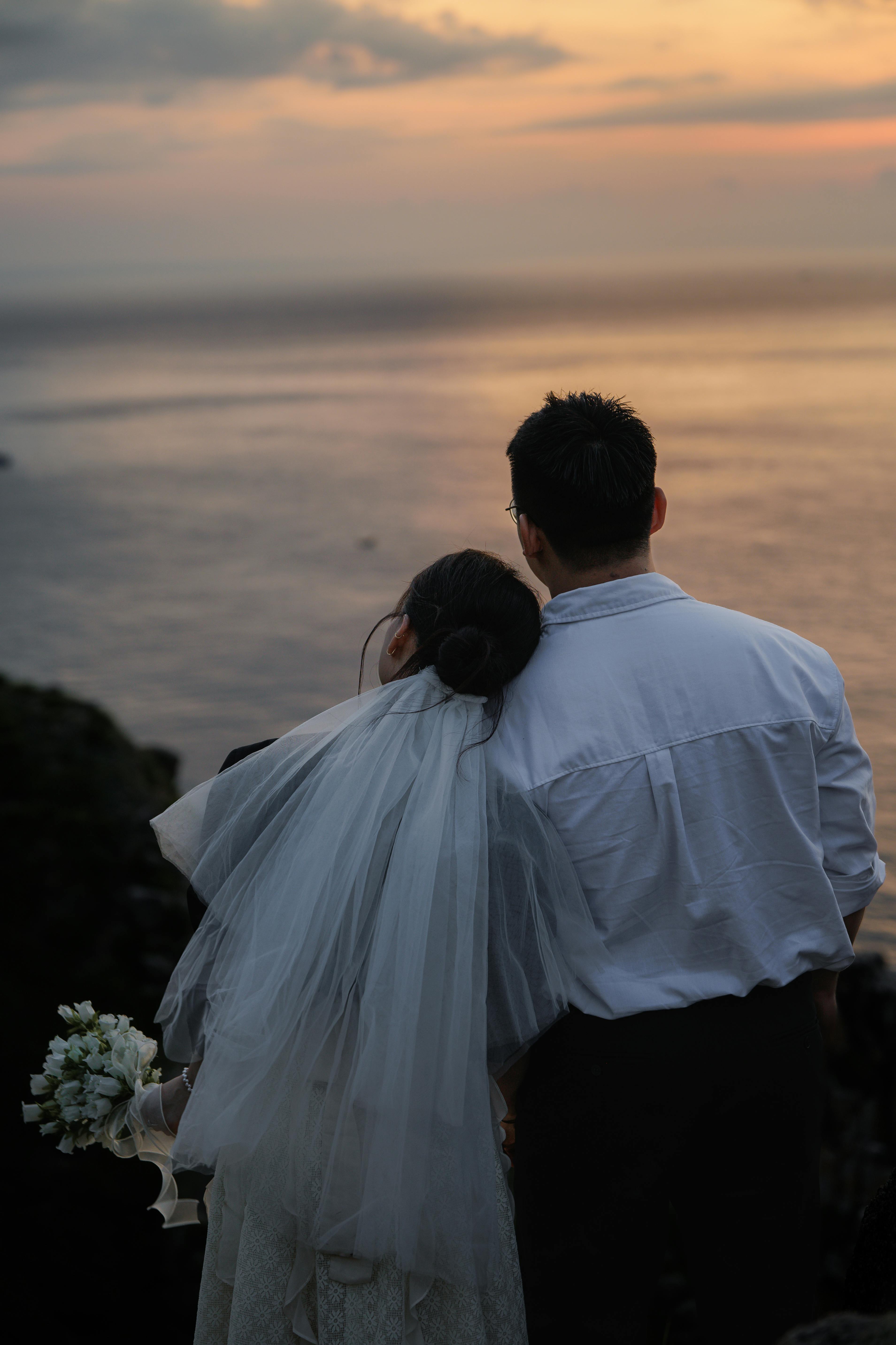 在日落时分，新娘和新郎在海边拥抱，捕捉浪漫的婚礼回忆