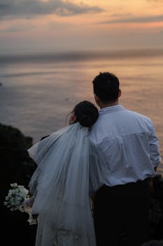 在日落时分，新娘和新郎在海边拥抱，捕捉浪漫的婚礼回忆