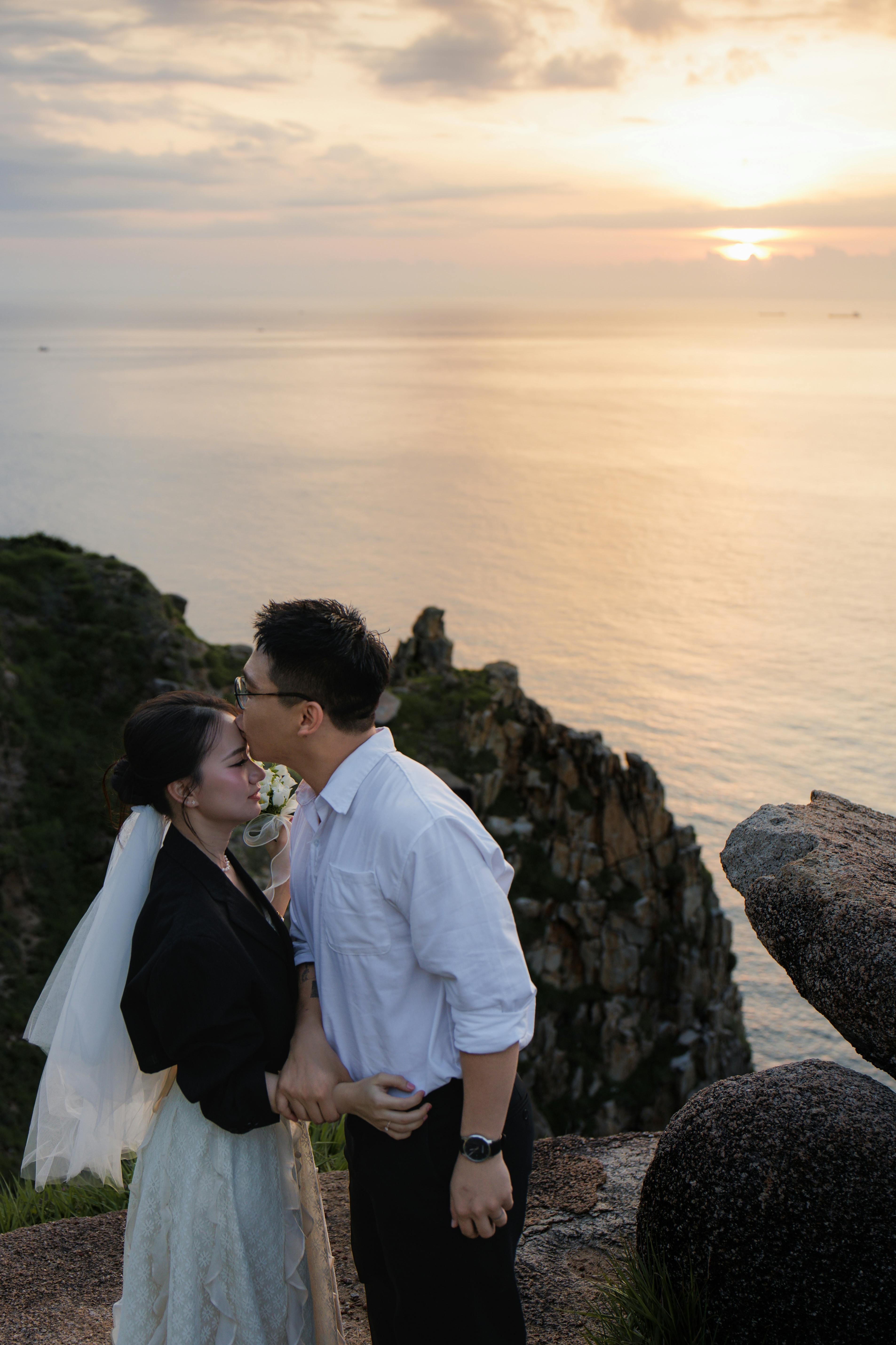 情侣在海边的悬崖上，共同分享着日落时分的温柔时刻