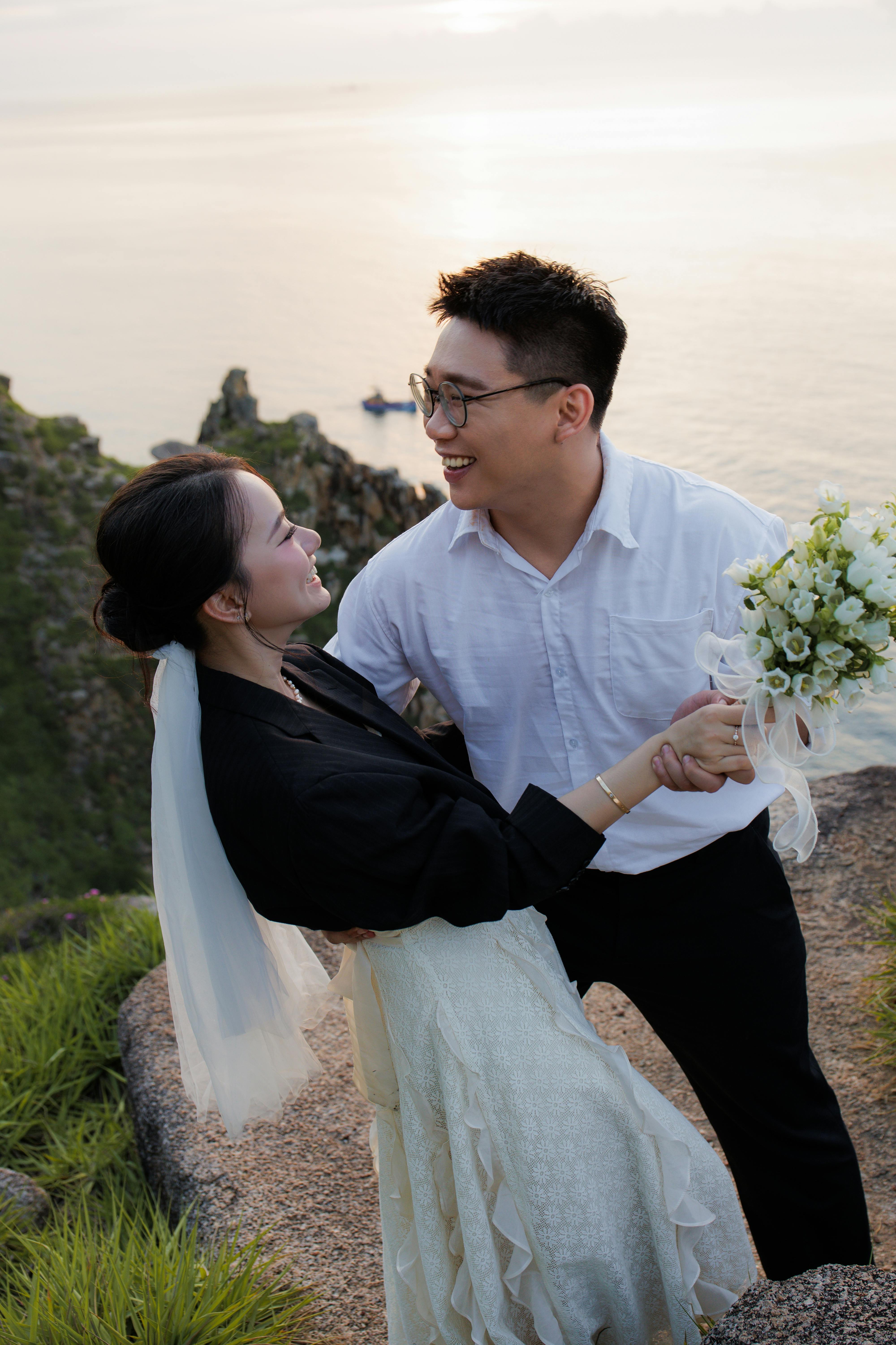 穿着优雅的新婚夫妇在日落时分，在海边户外摆姿势