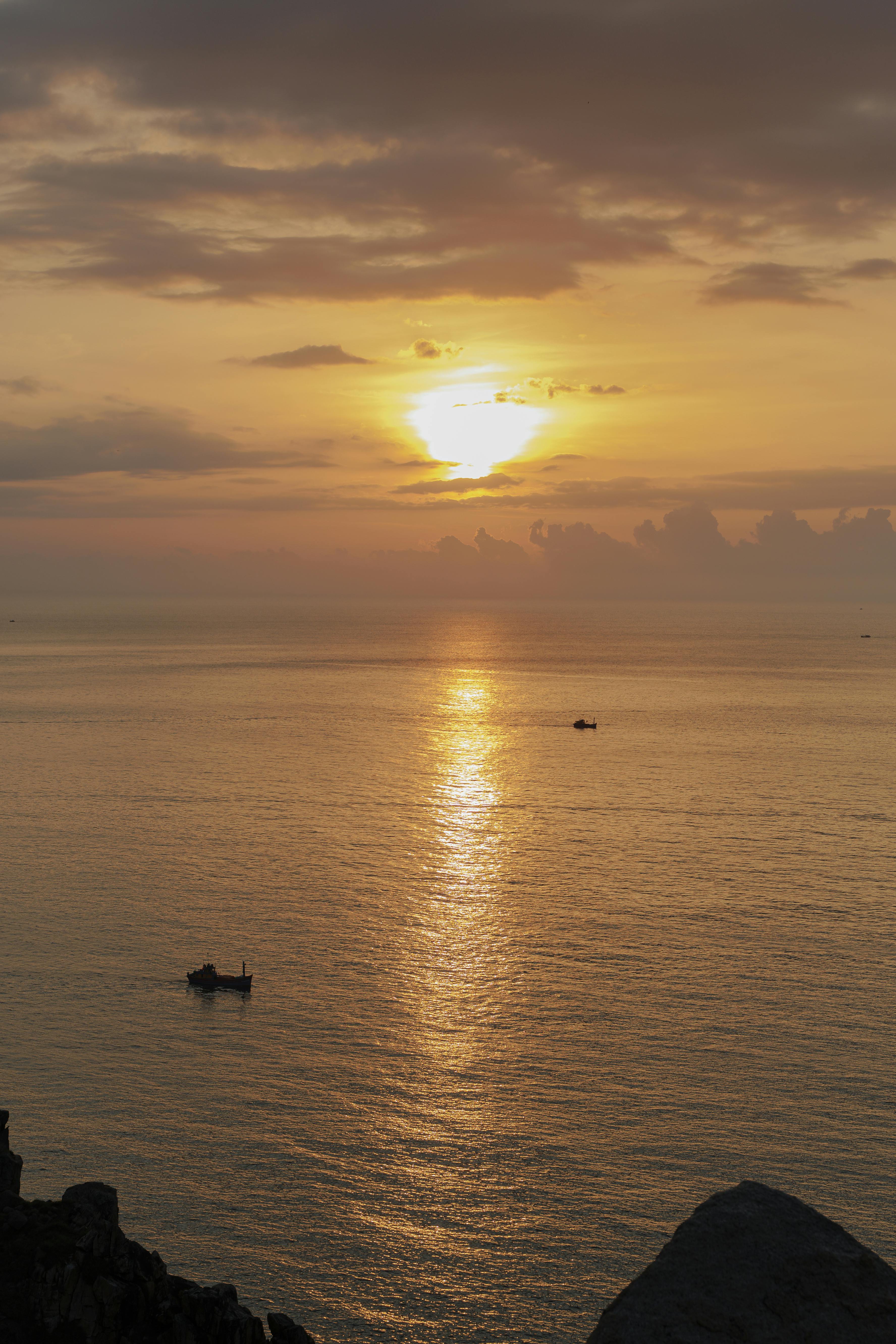 平静的海水上，宁静的日落映照着远方船只的轮廓