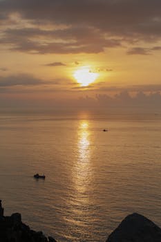 平静的海水上，宁静的日落映照着远方船只的轮廓