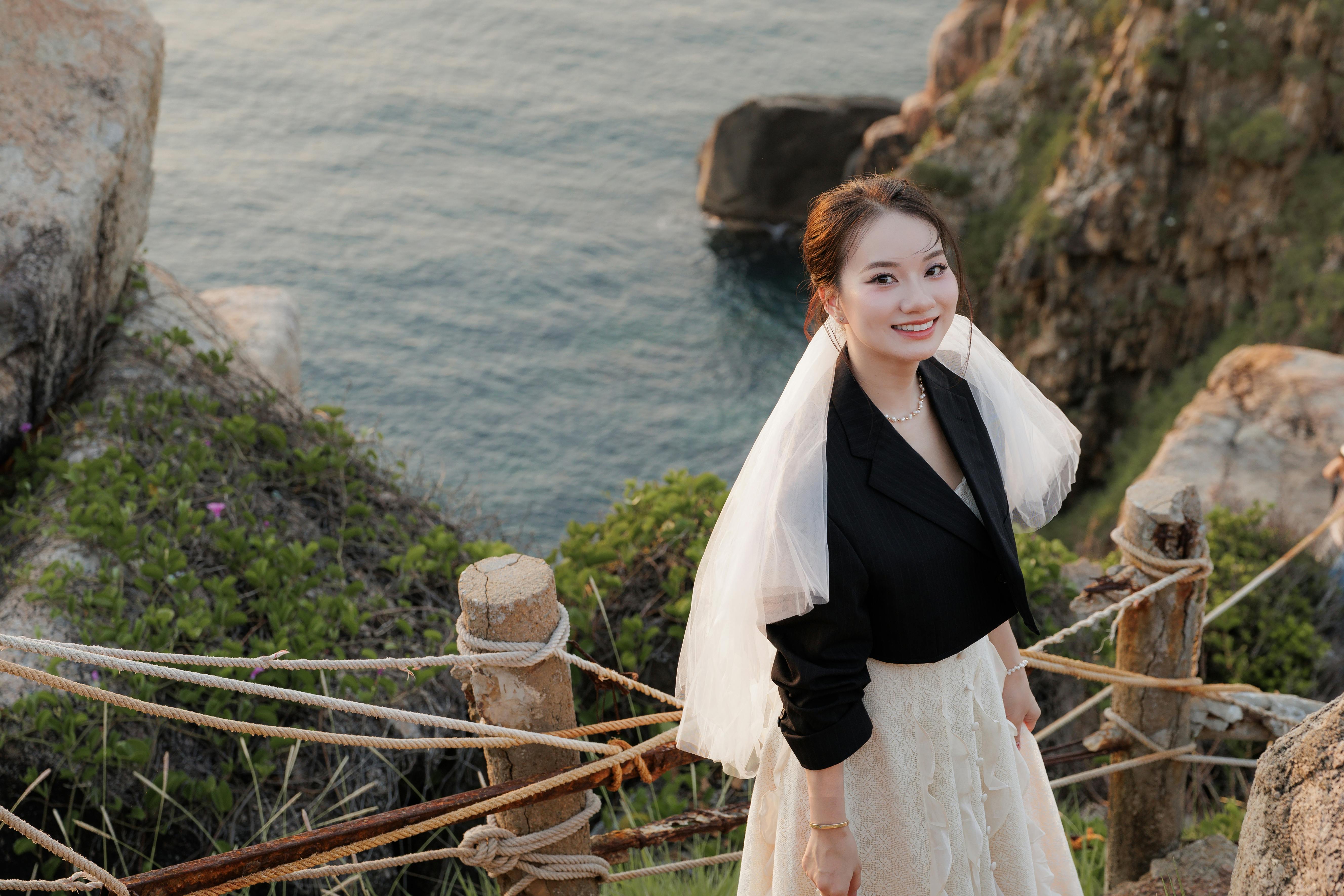在美丽海景的悬崖边，新娘微笑着，散发着优雅和欢乐