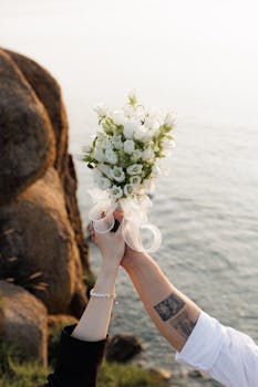 在日出时分，双手捧着新娘花束越过海崖，象征着团结