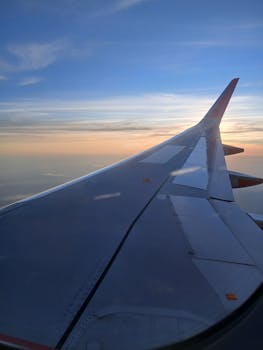 在飞机的窗户前，捕捉那令人惊叹的日落景色，让机翼在鲜艳的天空中显得格外引人注目