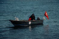 在伊斯坦布尔博斯普鲁斯海峡上，一艘小渔船上有一只海鸥和土耳其国旗