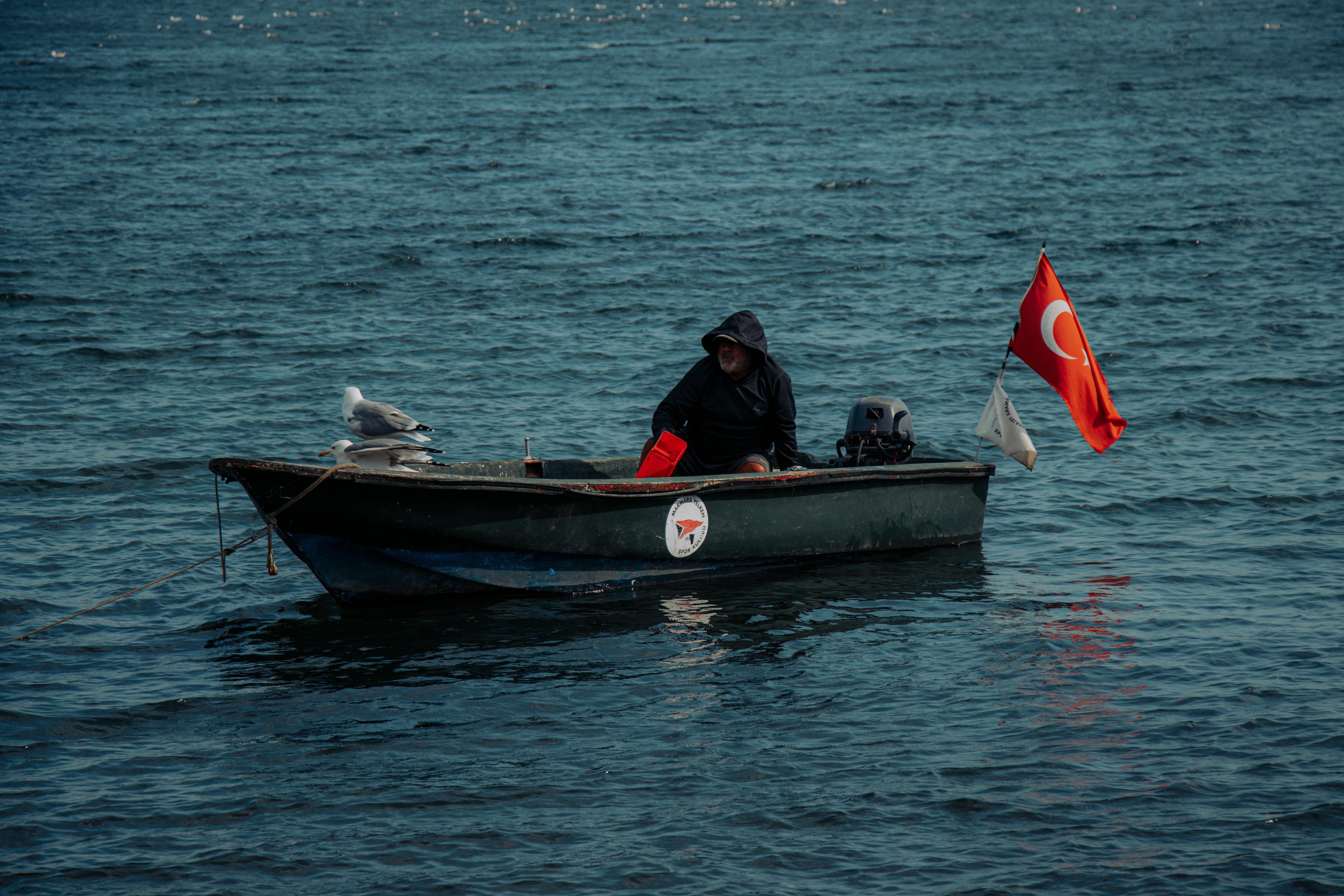 在博斯普鲁斯海峡，一名孤独的渔民乘坐一艘悬挂土耳其国旗的小船航行