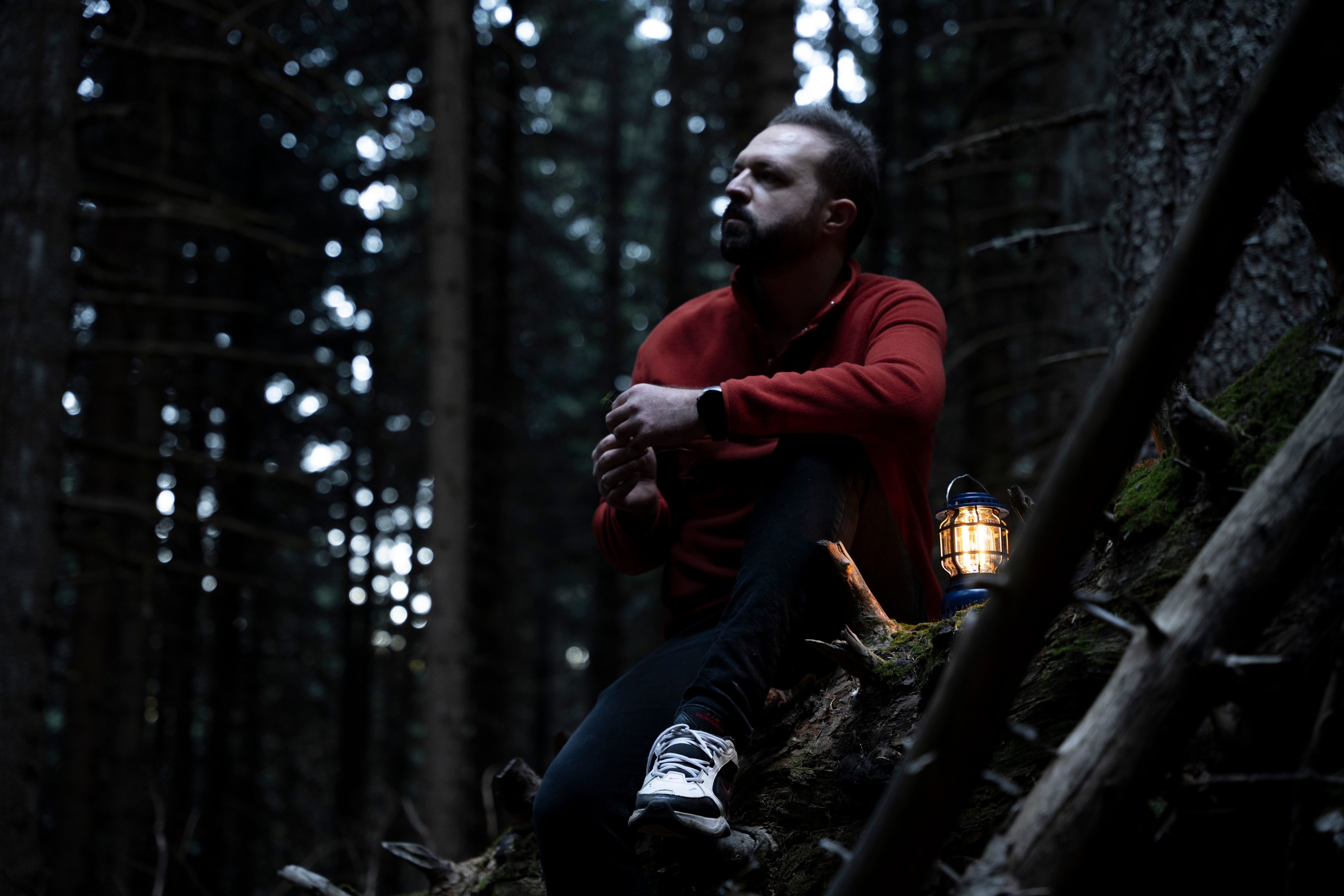 Mies otsalamppu päässä pimeässä metsässä