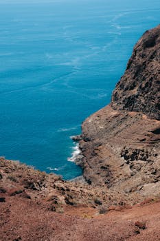 Scenic view of the rugged cliffs meeting the clear blue Atlantic in Alajeró, Canary Islands.