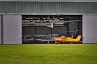 在阳光明媚的日子里，一架充满活力的黄色飞机停在满飞机的机库外