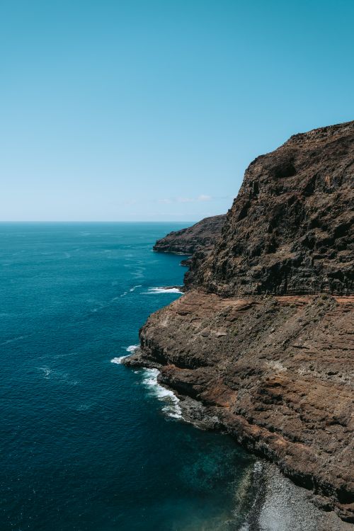 Free Stunning view of La Gomera's volcanic cliffs meeting the deep blue ocean under a clear sky. Stock Photo