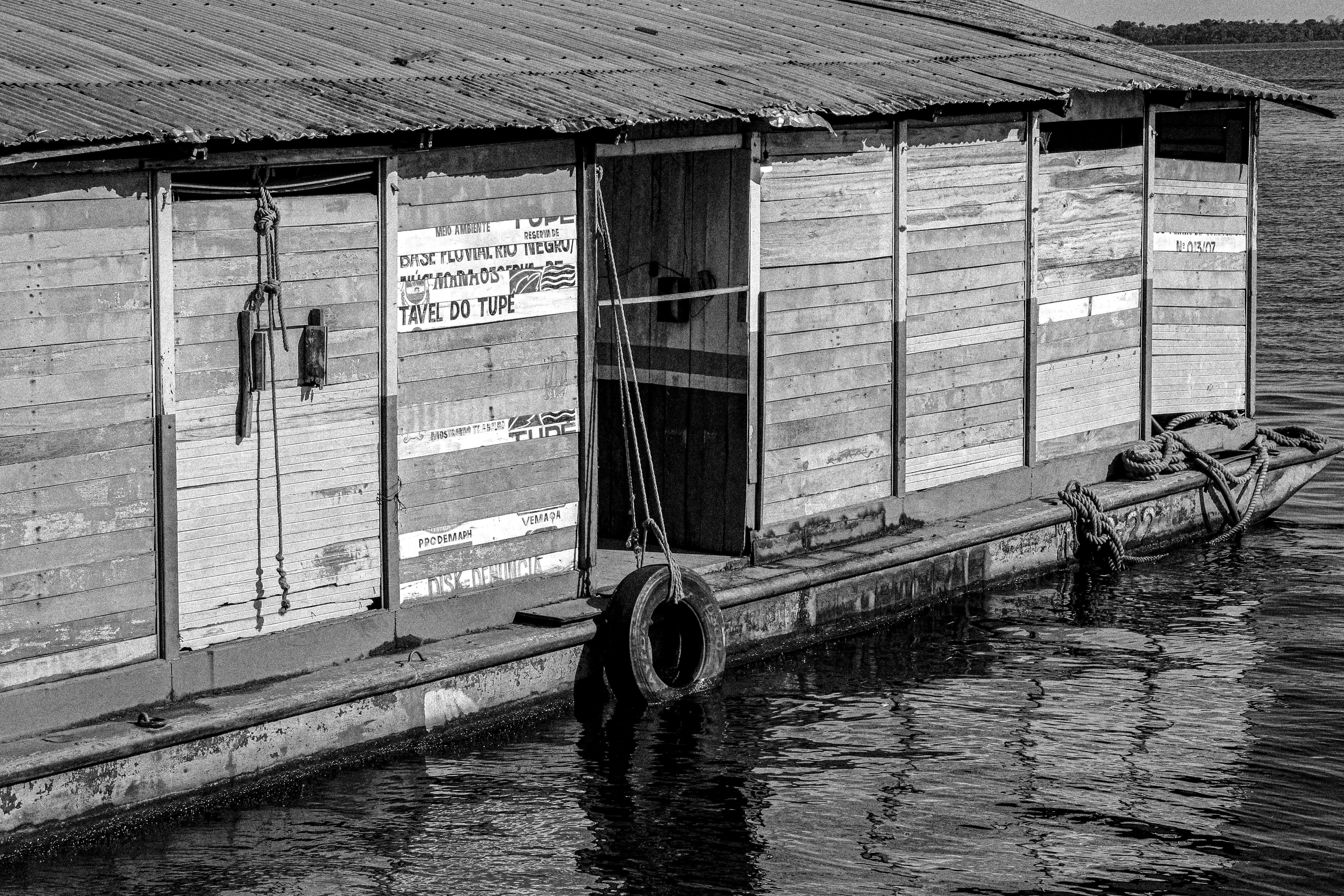Black and white photo of a floating house with reflective river surface.