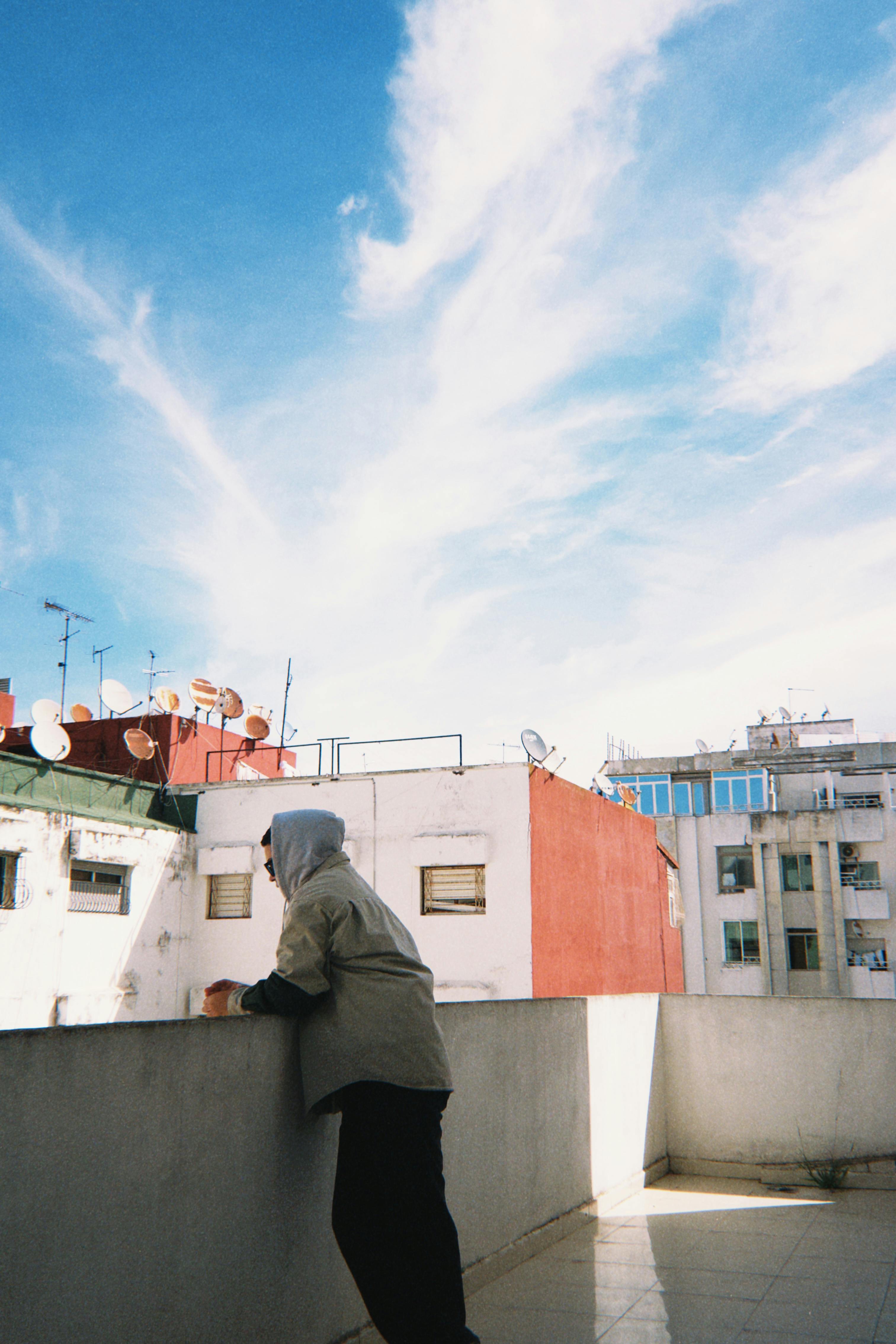 屋顶上的人在充满活力的蓝天下凝视着城市建筑