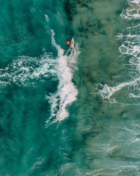 Top view of a surfer in turquoise Greek waters, capturing the thrill of surfing.
