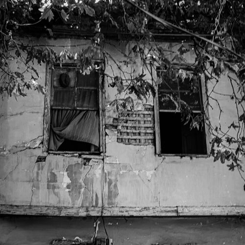 Free Black and white photo of an old, abandoned building with broken windows and peeling paint. Stock Photo