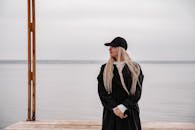 在阴天的海边，一名黑衣女子静静地站着，这是一段宁静的时刻