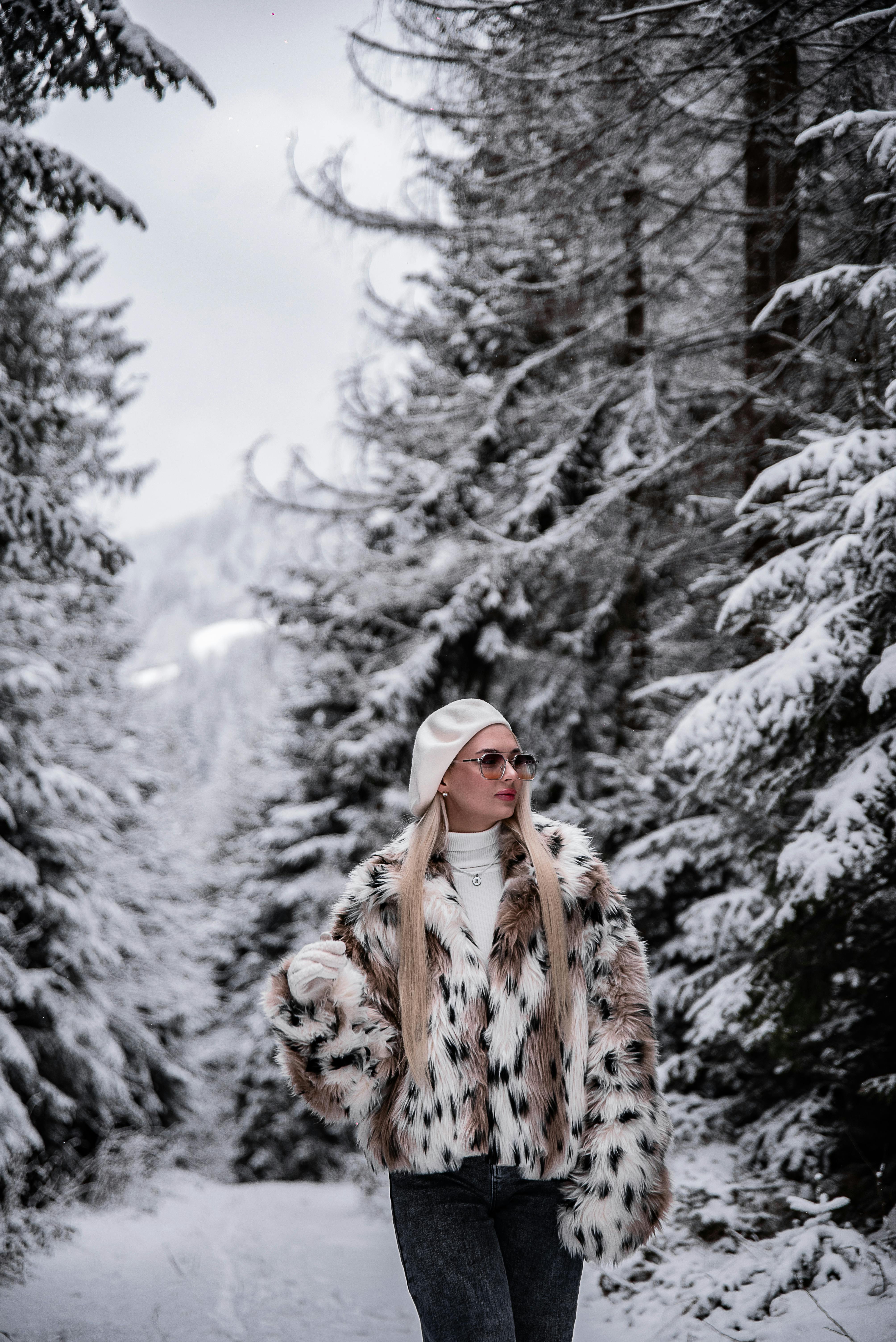 Uma mulher elegante com um casaco de pele caminha por uma floresta nevada durante o inverno.