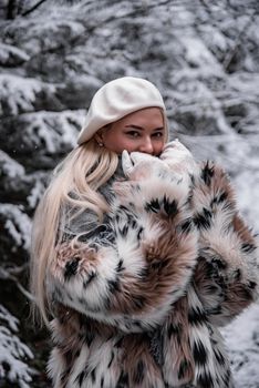 Stylish woman in faux fur coat and beret amidst a snowy forest, capturing winter fashion.