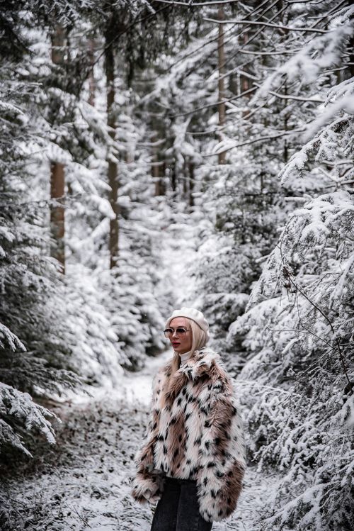 Free A woman in a fur coat standing in a serene, snow-covered forest, embodying winter elegance. Stock Photo