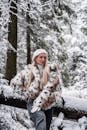 穿着时尚毛皮大衣的女人站在白雪皑皑的森林场景中