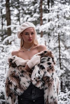 Stylish young woman in fur coat in a snow-covered forest.