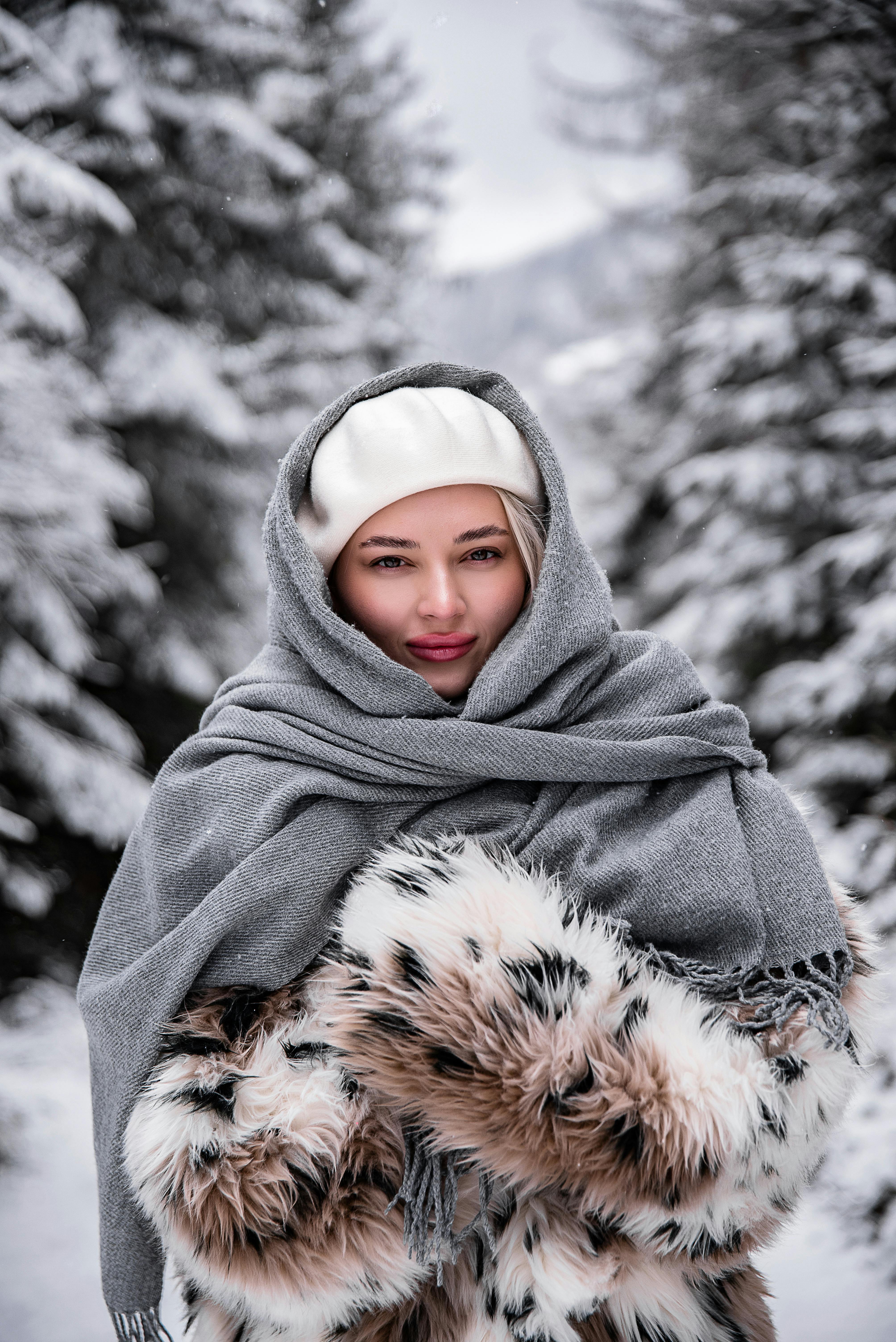 穿着冬装的女人被白雪覆盖的树木包围
