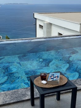 Infinity pool with sea view, table, and book for ultimate relaxation.