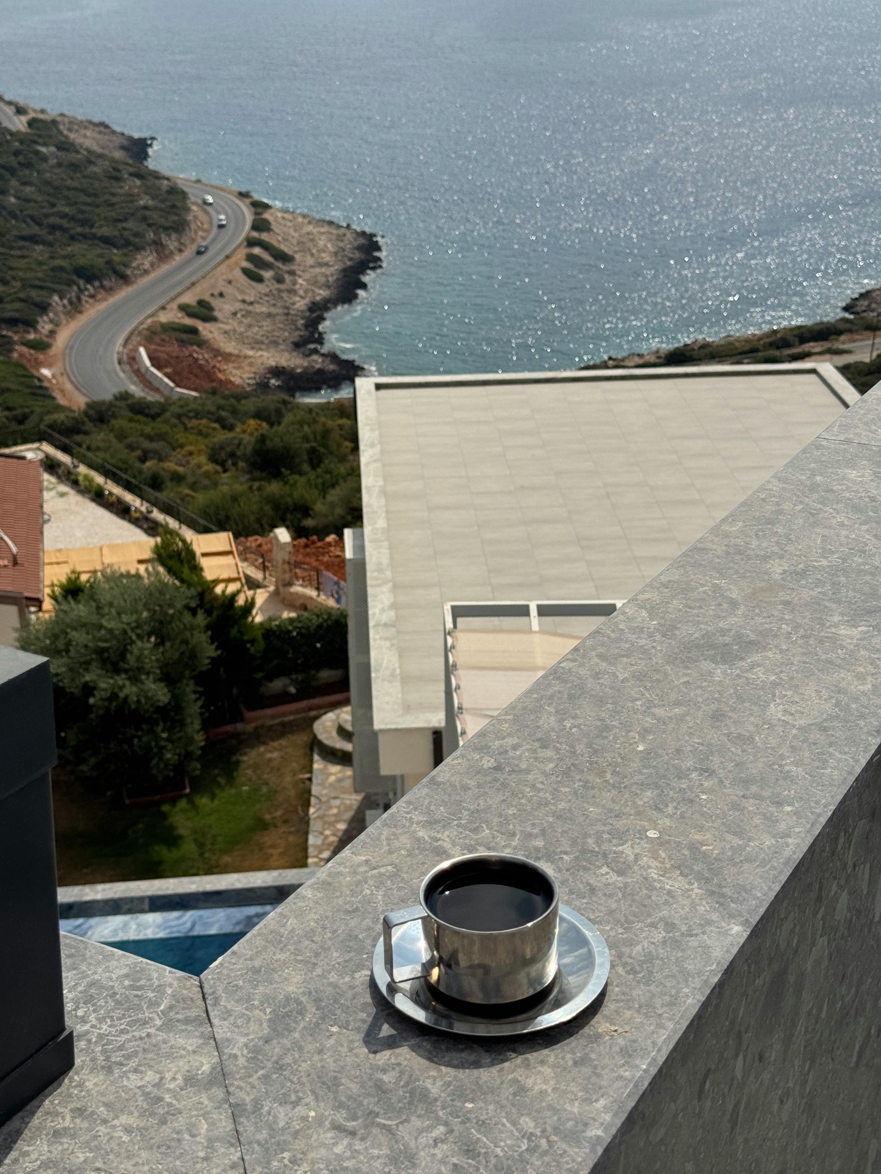 在阳台上，我享受着一杯香浓的咖啡，同时眺望着风景如画的海岸线和曲折蜿蜒的道路