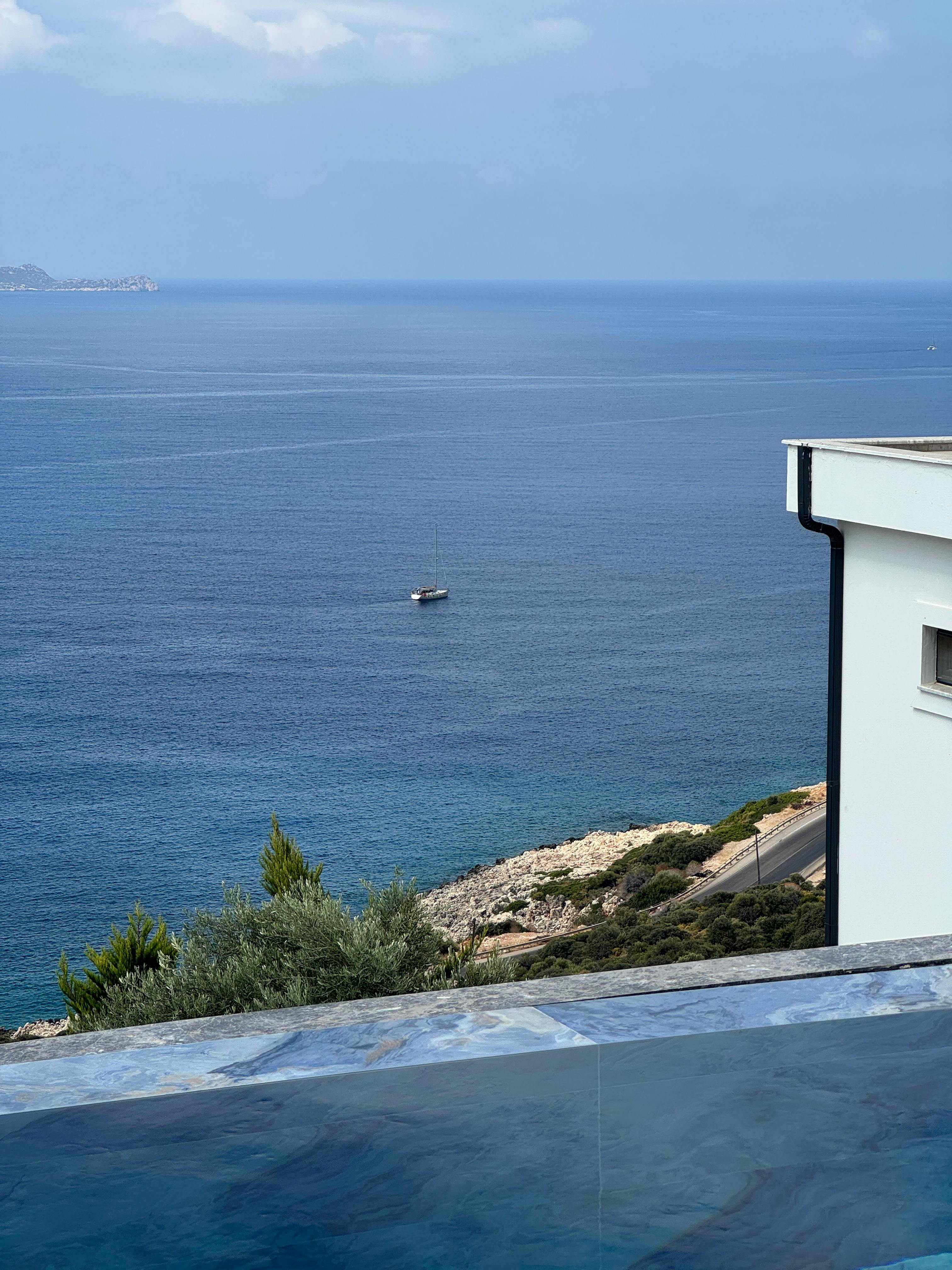 豪华的无边泳池旁，海景宁静而美丽，一艘孤独的船静静地漂浮在水面上